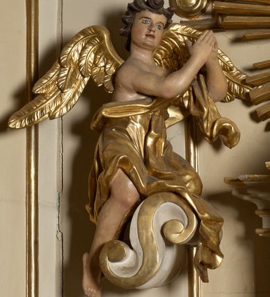 Zdjęcie nr 14: Ołtarz typu architektonicznego, jednokondygnacyjny, jednoosiowy, z bramkami i ze zwieńczeniem w formie glorii. Mensa prostopadłościenna, na ściance przedniej zdobiona rzędem płycin w kształcie stojącego prostokąta, zamkniętych łukiem nadwieszonym. W polu środkowej płyciny malowany krzyż grecki, w pozostałych gałązki białych lilii. Tabernakulum w formie prostopadłościennej skrzynki, z częścią środkową wysuniętą do przodu, zamknięte od góry profilowanym gzymsem w kształcie łuku nadwieszonego. Drzwiczki metalowe, pośrodku dekorowane płyciną w kształcie stojącego prostokąta, zamkniętego łukiem nadwieszonym, w polu kielich z hostią, kłosy zboża i kiście winogron. Nad tabernakulum tron wystawienia na tle promienistej glorii z monogramem IHS pośrodku, po bokach flankowany przez parę aniołków usadzonych na wolutach. Retabulum ustawione na wysokim cokole, ujęte parą zdwojonych, ukośnie ustawionych pilastrów podtrzymujących przerywane belkowanie, na którym usadzona para putt. Trzony pilastrów zdobione kanelowaniem, kapitele stylizowane, kompozytowe. Putto po lewej stronie z otwartą księgą, w której znajduje się napis: „Assu/pta / est / Maria / in / Caelum”. W polu głównym nastawy, na wysokości dwóch trzecich obraz z przedstawieniem Wniebowzięcia Najświętszej Marii Panny. Po bokach obrazu para rzeźbionych aniołków. W zwieńczeniu płaskorzeźba Boga Ojca na tle promienistej glorii. Drzwiczki bramek zdobione płyciną w kształcie stojącego prostokąta, zamkniętą od góry łukiem nadwieszonym. Zwieńczenie bramek zdobione festonem z liści wawrzynu, zakończone niskim cokołem, na którym ustawione rzeźby: po lewej św. Jana Chrzciciela, po prawej św. Kazimierza. Uszy ażurowe w postaci ornamentu rocaille'owego. Struktura ołtarza w kolorze beżowym, ornamentyka, detale i profilowania złocone.