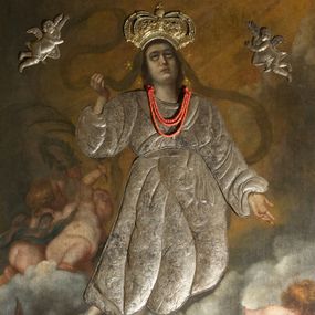 Zdjęcie nr 1: Obraz w kształcie stojącego prostokąta z przedstawieniem Wniebowzięcia Najświętszej Marii Panny. W centrum kompozycji ukazana Matka Boska unosząca się na chmurze obłoków, z ugiętymi w kolanach nogami, z prawą ręką wzniesioną do góry, lewą odsuniętą w bok, z głową lekko uniesioną do góry. Strój zasłonięty metalową, trybowaną sukienką. Twarz szeroka, z długim i wąskim nosem, wzrokiem skierowanym ku górze, włosy ciemne schowane pod metalową koroną; u szyi trzy sznury czerwonych korali. Wokół głowy nimb ze złotych gwiazd, a na głowie metalowa korona zamknięta. W dolnej części kompozycji grupka nagich putt w ekspresyjnych pozach, ukazane z różnych ujęć, z akcentem zielonej tkaniny, która przebiega pomiędzy nimi. Druga grupka putt nieco wyżej, po lewej stronie obrazu: jedno trzyma wianek, drugie zieloną gałązkę palmy. W górnej części obrazu, po bokach Marii, przybite dwa aniołki z blachy. Sukienka ozdobiona grawerowaną, bujną wicią roślinną z wielopłatkowymi kwiatami i liśćmi akantu. Tło ciemne w odcieniach szarości i brązu.

