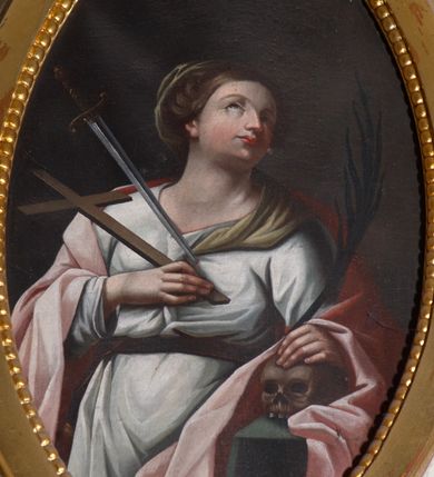 Zdjęcie nr 2: Obraz w kształcie owalu. W centrum kompozycji ukazana św. Wiktoria, w postawie stojącej, w trzech czwartych, z głową zwróconą w swoją lewą stronę i uniesioną delikatnie do góry. Lewa ręka świętej wsparta na leżącej na stoliku czaszce, podtrzymuje palmę męczeństwa w dłoni, a prawa trzyma przy piersi krzyż. Twarz o delikatnych rysach, długim i wąskim nosie, wzroku skierowanym do góry. Włosy ciemnobrązowe, upięte do tyłu, za nałożonym welonem na upięcie, spływającym na lewe ramię. Święta ubrana w długą białą suknię z długimi rękawami, przewiązaną w talii brązowym paskiem oraz jasnoróżowy płaszcz swobodnie założony na plecy. Z lewej strony obrazu serce św. Wiktorii przeszywa miecz. Stół zasłany jest zielonym obrusem. Tło jednolite, ciemnobrązowe. 

