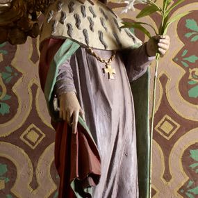 Zdjęcie nr 1: Rzeźba wolnostojąca, ukazująca św. Kazimierza, ustawiona na niskim cokole. Święty przedstawiony w całej postaci, w postawie stojącej z gałązką białej lilii w lewej dłoni, prawą dłonią przytrzymujący połę płaszcza. Twarz owalna, z wyraźnie zaznaczonym podbródkiem, z wąskimi ustami i wzrokiem skierowanym przed siebie; włosy długie i ciemnobrązowe opadające na plecy. Ubrany jest w długą, fioletową suknię z długimi rękawami, czerwony płaszcz z zieloną podszewką i gronostajową pelerynką, mitrę książęcą, zwieńczoną krzyżykiem na głowie oraz krzyżyk zawieszony na piersi na długim łańcuszku, na stopach buty. Polichromia w odsłoniętych partiach ciała naturalistyczna. 

