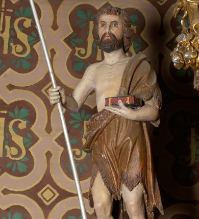 Zdjęcie nr 1: Rzeźba wolnostojąca, przedstawia św. Jana Chrzciciela, ustawiona na niskim, zielonym cokole na planie kwadratu. Święty ukazany frontalnie, w postawie stojącej z krzyżem o długim drzewcu w prawej dłoni oraz zamkniętą księgą w lewej. Twarz podłużna z długim i wąskim nosem, ze wzrokiem skierowanym w dal, okolona brązową, średniej długości brodą oraz krótkimi włosami, zasłaniającymi uszy.  Święty jest ubrany w szatę uszytą ze skóry zwierzęcej, odsłaniającą nagi tors i nogi poniżej kolan. Sylwetka szczupła. Polichromia w odsłoniętych partiach ciała naturalistyczna. 