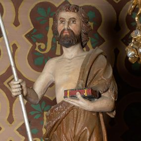 Zdjęcie nr 1: Rzeźba wolnostojąca, przedstawia św. Jana Chrzciciela, ustawiona na niskim, zielonym cokole na planie kwadratu. Święty ukazany frontalnie, w postawie stojącej z krzyżem o długim drzewcu w prawej dłoni oraz zamkniętą księgą w lewej. Twarz podłużna z długim i wąskim nosem, ze wzrokiem skierowanym w dal, okolona brązową, średniej długości brodą oraz krótkimi włosami, zasłaniającymi uszy.  Święty jest ubrany w szatę uszytą ze skóry zwierzęcej, odsłaniającą nagi tors i nogi poniżej kolan. Sylwetka szczupła. Polichromia w odsłoniętych partiach ciała naturalistyczna. 