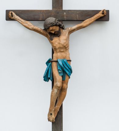 Zdjęcie nr 1: Rzeźba Chrystusa przybita do krzyża trzema gwoździami. Chrystus został ukazany w typie Cristo morte, w delikatnym zwisie, o szeroko rozłożonych ramionach, z głową skłonioną na prawe ramię, stopami założonymi prawa na lewą. Biodra ma przewiązane niebieskim perizonium wiszącym na pojedynczym sznurze, dwukrotnie przez niego przełożonym, odsłaniającym prawe biodro. Chrystus ma podłużną twarz, z wąskim nosem, zamkniętymi oczami, okoloną krótką i ciemnobrązową brodą; włosy długie i ciemnobrązowe, spływające na plecy i prawe ramię. Na głowie ma założoną koronę cierniową. Jego ciało jest szczupłe, o wyraźnie podkreślonej linii żeber i mostka. Na odwrociu krzyża napis „dnia V MAIA 1956 R[OKU] / MARIA KOSER / MALOWAŁA”. Krzyż prosty, gładki, malowany na kolor ciemnobrązowy. Polichromia ciała naturalistyczna.


 