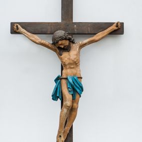 Zdjęcie nr 1: Rzeźba Chrystusa przybita do krzyża trzema gwoździami. Chrystus został ukazany w typie Cristo morte, w delikatnym zwisie, o szeroko rozłożonych ramionach, z głową skłonioną na prawe ramię, stopami założonymi prawa na lewą. Biodra ma przewiązane niebieskim perizonium wiszącym na pojedynczym sznurze, dwukrotnie przez niego przełożonym, odsłaniającym prawe biodro. Chrystus ma podłużną twarz, z wąskim nosem, zamkniętymi oczami, okoloną krótką i ciemnobrązową brodą; włosy długie i ciemnobrązowe, spływające na plecy i prawe ramię. Na głowie ma założoną koronę cierniową. Jego ciało jest szczupłe, o wyraźnie podkreślonej linii żeber i mostka. Na odwrociu krzyża napis „dnia V MAIA 1956 R[OKU] / MARIA KOSER / MALOWAŁA”. Krzyż prosty, gładki, malowany na kolor ciemnobrązowy. Polichromia ciała naturalistyczna.


 