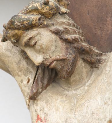 Zdjęcie nr 3: Rzeźba Chrystusa przybita do krzyża trzema gwoździami. Chrystus został ukazany w typie Cristo morte, w delikatnym zwisie, o szeroko rozłożonych ramionach, z głową skłonioną na prawe ramię, stopami założonymi prawa na lewą. Biodra ma przepasane złotym perizonium przewiązanym grubym sznurem, z jednym końcem zwisającym wzdłuż prawego uda, a powyżej tego fałdu ze sporym węzłem uformowanym z draperii powyżej sznura. Chrystus ma podłużną twarz, długi i wąski nos, zamknięte oczy, krótką brodę; włosy długie, ułożone w grube pukle, spływające na plecy i prawe ramię. Na głowie ma założoną szeroką koronę cierniową. Jego ciało jest szczupłe, o wyraźnie podkreślonej linii żeber, wąskiej talii. Nad głową Chrystusa umieszczona jest tabliczka z napisem „INRI” ujęta kartuszową ramą. Krzyż prosty, gładki, malowany na kolor ciemnobrązowy. Polichromia ciała naturalistyczna. Kartusz złocony i srebrzony.


 