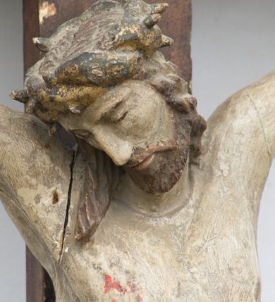 Zdjęcie nr 2: Rzeźba Chrystusa przybita do krzyża trzema gwoździami. Chrystus został ukazany w typie Cristo morte, w delikatnym zwisie, o szeroko rozłożonych ramionach, z głową skłonioną na prawe ramię, stopami założonymi prawa na lewą. Biodra ma przepasane złotym perizonium przewiązanym grubym sznurem, z jednym końcem zwisającym wzdłuż prawego uda, a powyżej tego fałdu ze sporym węzłem uformowanym z draperii powyżej sznura. Chrystus ma podłużną twarz, długi i wąski nos, zamknięte oczy, krótką brodę; włosy długie, ułożone w grube pukle, spływające na plecy i prawe ramię. Na głowie ma założoną szeroką koronę cierniową. Jego ciało jest szczupłe, o wyraźnie podkreślonej linii żeber, wąskiej talii. Nad głową Chrystusa umieszczona jest tabliczka z napisem „INRI” ujęta kartuszową ramą. Krzyż prosty, gładki, malowany na kolor ciemnobrązowy. Polichromia ciała naturalistyczna. Kartusz złocony i srebrzony.


 