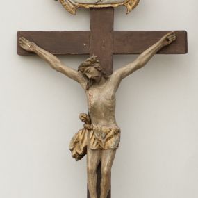 Zdjęcie nr 1: Rzeźba Chrystusa przybita do krzyża trzema gwoździami. Chrystus został ukazany w typie Cristo morte, w delikatnym zwisie, o szeroko rozłożonych ramionach, z głową skłonioną na prawe ramię, stopami założonymi prawa na lewą. Biodra ma przepasane złotym perizonium przewiązanym grubym sznurem, z jednym końcem zwisającym wzdłuż prawego uda, a powyżej tego fałdu ze sporym węzłem uformowanym z draperii powyżej sznura. Chrystus ma podłużną twarz, długi i wąski nos, zamknięte oczy, krótką brodę; włosy długie, ułożone w grube pukle, spływające na plecy i prawe ramię. Na głowie ma założoną szeroką koronę cierniową. Jego ciało jest szczupłe, o wyraźnie podkreślonej linii żeber, wąskiej talii. Nad głową Chrystusa umieszczona jest tabliczka z napisem „INRI” ujęta kartuszową ramą. Krzyż prosty, gładki, malowany na kolor ciemnobrązowy. Polichromia ciała naturalistyczna. Kartusz złocony i srebrzony.


 