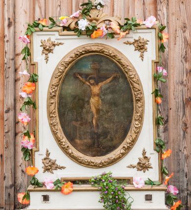 Zdjęcie nr 1: Feretron dwustronny z przedstawieniem Chrystusa Ukrzyżowanego oraz św. Izydora Oracza ustawiony na prostopadłościennym, zdwojonym cokole, zaopatrzonym w otwory na drążki do noszenia. Obrazy w kształcie owalu, ujęte prostokątną ramą z uszatymi narożami, w polu których płaskorzeźbione gałązki kwiatów. Rama wokół obrazu owalna, dekorowana drobnymi kwiatkami i opleciona karbowaną wstęgą. Zwieńczenie proste w formie stylizowanych liści akantu z zatkniętym u szczytu krzyżykiem łacińskim. Po jednej stronie feretronu obraz Ukrzyżowania Chrystusa. W centrum kompozycji ukazany krucyfiks z Chrystusem przybitym do krzyża trzema gwoździami, z głową przechyloną na prawe ramię. Wokół bioder białe perizonium. Na głowie korona cierniowa i kolisty nimb. Sylwetka szczupła, z poprawnie zaznaczoną anatomią. Nad głową Chrystusa tabliczka z tytułem winy: „INRI”. Po lewej stronie obrazu Matka Boska oraz św. Jan Ewangelista ukazani w postawie stojącej, zwróceni w stronę krzyża. U stóp krzyża wąż. Pozostałe elementy nieczytelne z powodu znacznego zniszczenia obrazu. Po drugiej stronie feretronu przedstawiono św. Izydora Oracza. Święty Izydor ukazany w pozycji klęczącej przed kapliczką, zwrócony delikatnie trzy czwarte w swoją prawą stronę, ze skrzyżowanymi na piersi dłońmi. Ubrany w rozpięty żupan przewiązany pasem, pod spodem biała i długa koszula. Twarz szeroka, włosy sięgające do ramion, z grzywką. Po prawej stronie kompozycji, w tle anioł orzący pole. Kapliczka ustawiona na zdwojonym, wysokim cokole podtrzymującym zabudowaną niszę, w której umieszczony krucyfiks. U kolan świętego kapelusz i kij. Tło jasne, w górnej części błękitne niebo. Struktura feretronu polichromowana na biało, detale i ornamemtyka złocone. 