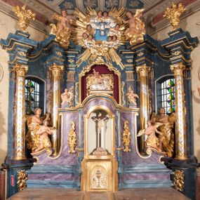 Zdjęcie nr 1: Nastawa ołtarzowa architektoniczna, trójosiowa, jednokondygnacyjna, ustawiona na wysokim cokole. Ołtarz wolnostojący, odsunięty od retabulum, drewniany, sarkofagowy z drewnianą mensą, na nim ustawione tabernakulum. Nastawa opasująca trójbocznie zamknięte prezbiterium, osie wydzielone czterema parami pilastrów o trzonach dekorowanych rocaille'em, przed którymi stoją cztery kolumny o kapitelach kompozytowych i trzonach z dekoracją geometryczną, dźwigających imposty. W polu środkowym nisza w formie stojącego prostokąta zamkniętego łukiem segmentowym nadwieszonym z uskokiem, ujęta profilowaną ramą dekorowaną rocaille'em z dużo mniejszym obrazem Matki Boskiej Nieustającej Pomocy w osobnej ramie na czerwonym tle. Osie boczne przeprute oknami w formie stojącego prostokąta zamkniętego łukiem segmentowym, na ich tle stoją figury aniołów. Nad polem głównym medalion z obłoków i uskrzydlonych główek anielskich z gołębicą Ducha Świętego w glorii promienistej. Na belkowaniu, na osi wewnętrznych impostów dwa siedzące na obłokach putta, na osi zewnętrznych rokokowe wazony. Nastawa flankowana dwoma przyściennymi cokołami, na których stoją figury św. Piotra i św. Pawła. Struktura architektoniczna polichromowana na sposób imitujący niebiesko-białą marmoryzację, trzony pilastrów fioletową. Ornamentyka, profile, kolumny i gloria pozłacane i posrebrzane. 
 





