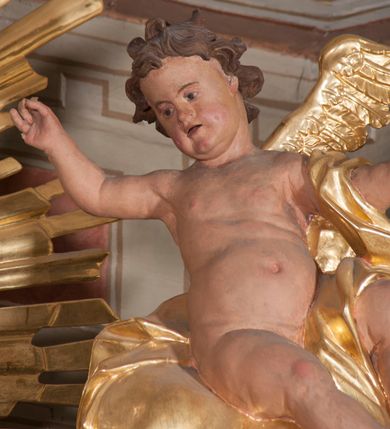 Zdjęcie nr 7: Nastawa ołtarzowa architektoniczna, trójosiowa, jednokondygnacyjna, ustawiona na wysokim cokole. Ołtarz wolnostojący, odsunięty od retabulum, drewniany, sarkofagowy z drewnianą mensą, na nim ustawione tabernakulum. Nastawa opasująca trójbocznie zamknięte prezbiterium, osie wydzielone czterema parami pilastrów o trzonach dekorowanych rocaille'em, przed którymi stoją cztery kolumny o kapitelach kompozytowych i trzonach z dekoracją geometryczną, dźwigających imposty. W polu środkowym nisza w formie stojącego prostokąta zamkniętego łukiem segmentowym nadwieszonym z uskokiem, ujęta profilowaną ramą dekorowaną rocaille'em z dużo mniejszym obrazem Matki Boskiej Nieustającej Pomocy w osobnej ramie na czerwonym tle. Osie boczne przeprute oknami w formie stojącego prostokąta zamkniętego łukiem segmentowym, na ich tle stoją figury aniołów. Nad polem głównym medalion z obłoków i uskrzydlonych główek anielskich z gołębicą Ducha Świętego w glorii promienistej. Na belkowaniu, na osi wewnętrznych impostów dwa siedzące na obłokach putta, na osi zewnętrznych rokokowe wazony. Nastawa flankowana dwoma przyściennymi cokołami, na których stoją figury św. Piotra i św. Pawła. Struktura architektoniczna polichromowana na sposób imitujący niebiesko-białą marmoryzację, trzony pilastrów fioletową. Ornamentyka, profile, kolumny i gloria pozłacane i posrebrzane. 
 





