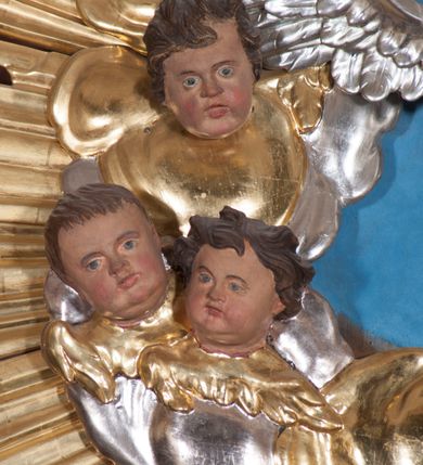 Zdjęcie nr 3: Nastawa ołtarzowa architektoniczna, trójosiowa, jednokondygnacyjna, ustawiona na wysokim cokole. Ołtarz wolnostojący, odsunięty od retabulum, drewniany, sarkofagowy z drewnianą mensą, na nim ustawione tabernakulum. Nastawa opasująca trójbocznie zamknięte prezbiterium, osie wydzielone czterema parami pilastrów o trzonach dekorowanych rocaille'em, przed którymi stoją cztery kolumny o kapitelach kompozytowych i trzonach z dekoracją geometryczną, dźwigających imposty. W polu środkowym nisza w formie stojącego prostokąta zamkniętego łukiem segmentowym nadwieszonym z uskokiem, ujęta profilowaną ramą dekorowaną rocaille'em z dużo mniejszym obrazem Matki Boskiej Nieustającej Pomocy w osobnej ramie na czerwonym tle. Osie boczne przeprute oknami w formie stojącego prostokąta zamkniętego łukiem segmentowym, na ich tle stoją figury aniołów. Nad polem głównym medalion z obłoków i uskrzydlonych główek anielskich z gołębicą Ducha Świętego w glorii promienistej. Na belkowaniu, na osi wewnętrznych impostów dwa siedzące na obłokach putta, na osi zewnętrznych rokokowe wazony. Nastawa flankowana dwoma przyściennymi cokołami, na których stoją figury św. Piotra i św. Pawła. Struktura architektoniczna polichromowana na sposób imitujący niebiesko-białą marmoryzację, trzony pilastrów fioletową. Ornamentyka, profile, kolumny i gloria pozłacane i posrebrzane. 
 





