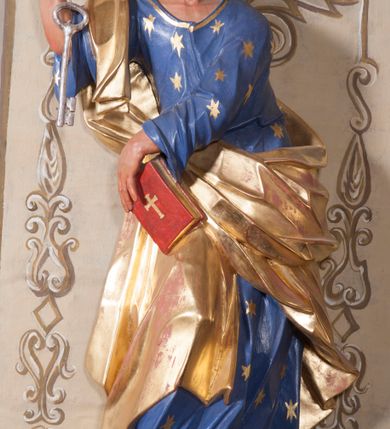 Zdjęcie nr 20: Nastawa ołtarzowa architektoniczna, trójosiowa, jednokondygnacyjna, ustawiona na wysokim cokole. Ołtarz wolnostojący, odsunięty od retabulum, drewniany, sarkofagowy z drewnianą mensą, na nim ustawione tabernakulum. Nastawa opasująca trójbocznie zamknięte prezbiterium, osie wydzielone czterema parami pilastrów o trzonach dekorowanych rocaille&#039;em, przed którymi stoją cztery kolumny o kapitelach kompozytowych i trzonach z dekoracją geometryczną, dźwigających imposty. W polu środkowym nisza w formie stojącego prostokąta zamkniętego łukiem segmentowym nadwieszonym z uskokiem, ujęta profilowaną ramą dekorowaną rocaille&#039;em z dużo mniejszym obrazem Matki Boskiej Nieustającej Pomocy w osobnej ramie na czerwonym tle. Osie boczne przeprute oknami w formie stojącego prostokąta zamkniętego łukiem segmentowym, na ich tle stoją figury aniołów. Nad polem głównym medalion z obłoków i uskrzydlonych główek anielskich z gołębicą Ducha Świętego w glorii promienistej. Na belkowaniu, na osi wewnętrznych impostów dwa siedzące na obłokach putta, na osi zewnętrznych rokokowe wazony. Nastawa flankowana dwoma przyściennymi cokołami, na których stoją figury św. Piotra i św. Pawła. Struktura architektoniczna polichromowana na sposób imitujący niebiesko-białą marmoryzację, trzony pilastrów fioletową. Ornamentyka, profile, kolumny i gloria pozłacane i posrebrzane. 
 





