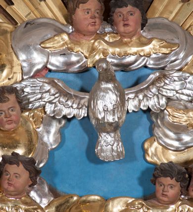 Zdjęcie nr 32: Nastawa ołtarzowa architektoniczna, trójosiowa, jednokondygnacyjna, ustawiona na wysokim cokole. Ołtarz wolnostojący, odsunięty od retabulum, drewniany, sarkofagowy z drewnianą mensą, na nim ustawione tabernakulum. Nastawa opasująca trójbocznie zamknięte prezbiterium, osie wydzielone czterema parami pilastrów o trzonach dekorowanych rocaille'em, przed którymi stoją cztery kolumny o kapitelach kompozytowych i trzonach z dekoracją geometryczną, dźwigających imposty. W polu środkowym nisza w formie stojącego prostokąta zamkniętego łukiem segmentowym nadwieszonym z uskokiem, ujęta profilowaną ramą dekorowaną rocaille'em z dużo mniejszym obrazem Matki Boskiej Nieustającej Pomocy w osobnej ramie na czerwonym tle. Osie boczne przeprute oknami w formie stojącego prostokąta zamkniętego łukiem segmentowym, na ich tle stoją figury aniołów. Nad polem głównym medalion z obłoków i uskrzydlonych główek anielskich z gołębicą Ducha Świętego w glorii promienistej. Na belkowaniu, na osi wewnętrznych impostów dwa siedzące na obłokach putta, na osi zewnętrznych rokokowe wazony. Nastawa flankowana dwoma przyściennymi cokołami, na których stoją figury św. Piotra i św. Pawła. Struktura architektoniczna polichromowana na sposób imitujący niebiesko-białą marmoryzację, trzony pilastrów fioletową. Ornamentyka, profile, kolumny i gloria pozłacane i posrebrzane. 
 





