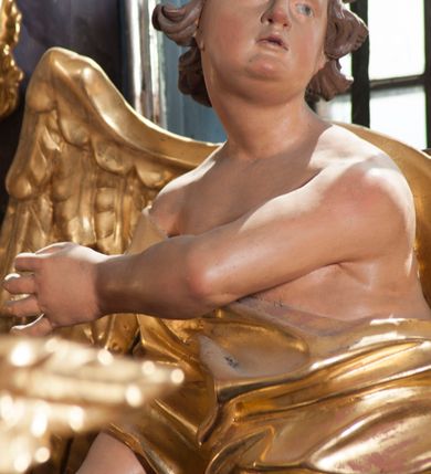 Zdjęcie nr 18: Nastawa ołtarzowa architektoniczna, trójosiowa, jednokondygnacyjna, ustawiona na wysokim cokole. Ołtarz wolnostojący, odsunięty od retabulum, drewniany, sarkofagowy z drewnianą mensą, na nim ustawione tabernakulum. Nastawa opasująca trójbocznie zamknięte prezbiterium, osie wydzielone czterema parami pilastrów o trzonach dekorowanych rocaille&#039;em, przed którymi stoją cztery kolumny o kapitelach kompozytowych i trzonach z dekoracją geometryczną, dźwigających imposty. W polu środkowym nisza w formie stojącego prostokąta zamkniętego łukiem segmentowym nadwieszonym z uskokiem, ujęta profilowaną ramą dekorowaną rocaille&#039;em z dużo mniejszym obrazem Matki Boskiej Nieustającej Pomocy w osobnej ramie na czerwonym tle. Osie boczne przeprute oknami w formie stojącego prostokąta zamkniętego łukiem segmentowym, na ich tle stoją figury aniołów. Nad polem głównym medalion z obłoków i uskrzydlonych główek anielskich z gołębicą Ducha Świętego w glorii promienistej. Na belkowaniu, na osi wewnętrznych impostów dwa siedzące na obłokach putta, na osi zewnętrznych rokokowe wazony. Nastawa flankowana dwoma przyściennymi cokołami, na których stoją figury św. Piotra i św. Pawła. Struktura architektoniczna polichromowana na sposób imitujący niebiesko-białą marmoryzację, trzony pilastrów fioletową. Ornamentyka, profile, kolumny i gloria pozłacane i posrebrzane. 
 





