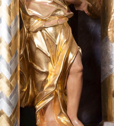 Zdjęcie nr 10: Nastawa ołtarzowa architektoniczna, trójosiowa, jednokondygnacyjna, ustawiona na wysokim cokole. Ołtarz wolnostojący, odsunięty od retabulum, drewniany, sarkofagowy z drewnianą mensą, na nim ustawione tabernakulum. Nastawa opasująca trójbocznie zamknięte prezbiterium, osie wydzielone czterema parami pilastrów o trzonach dekorowanych rocaille&#039;em, przed którymi stoją cztery kolumny o kapitelach kompozytowych i trzonach z dekoracją geometryczną, dźwigających imposty. W polu środkowym nisza w formie stojącego prostokąta zamkniętego łukiem segmentowym nadwieszonym z uskokiem, ujęta profilowaną ramą dekorowaną rocaille&#039;em z dużo mniejszym obrazem Matki Boskiej Nieustającej Pomocy w osobnej ramie na czerwonym tle. Osie boczne przeprute oknami w formie stojącego prostokąta zamkniętego łukiem segmentowym, na ich tle stoją figury aniołów. Nad polem głównym medalion z obłoków i uskrzydlonych główek anielskich z gołębicą Ducha Świętego w glorii promienistej. Na belkowaniu, na osi wewnętrznych impostów dwa siedzące na obłokach putta, na osi zewnętrznych rokokowe wazony. Nastawa flankowana dwoma przyściennymi cokołami, na których stoją figury św. Piotra i św. Pawła. Struktura architektoniczna polichromowana na sposób imitujący niebiesko-białą marmoryzację, trzony pilastrów fioletową. Ornamentyka, profile, kolumny i gloria pozłacane i posrebrzane. 
 





