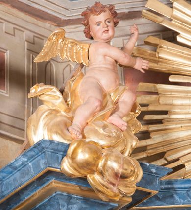 Zdjęcie nr 4: Nastawa ołtarzowa architektoniczna, trójosiowa, jednokondygnacyjna, ustawiona na wysokim cokole. Ołtarz wolnostojący, odsunięty od retabulum, drewniany, sarkofagowy z drewnianą mensą, na nim ustawione tabernakulum. Nastawa opasująca trójbocznie zamknięte prezbiterium, osie wydzielone czterema parami pilastrów o trzonach dekorowanych rocaille&#039;em, przed którymi stoją cztery kolumny o kapitelach kompozytowych i trzonach z dekoracją geometryczną, dźwigających imposty. W polu środkowym nisza w formie stojącego prostokąta zamkniętego łukiem segmentowym nadwieszonym z uskokiem, ujęta profilowaną ramą dekorowaną rocaille&#039;em z dużo mniejszym obrazem Matki Boskiej Nieustającej Pomocy w osobnej ramie na czerwonym tle. Osie boczne przeprute oknami w formie stojącego prostokąta zamkniętego łukiem segmentowym, na ich tle stoją figury aniołów. Nad polem głównym medalion z obłoków i uskrzydlonych główek anielskich z gołębicą Ducha Świętego w glorii promienistej. Na belkowaniu, na osi wewnętrznych impostów dwa siedzące na obłokach putta, na osi zewnętrznych rokokowe wazony. Nastawa flankowana dwoma przyściennymi cokołami, na których stoją figury św. Piotra i św. Pawła. Struktura architektoniczna polichromowana na sposób imitujący niebiesko-białą marmoryzację, trzony pilastrów fioletową. Ornamentyka, profile, kolumny i gloria pozłacane i posrebrzane. 
 





