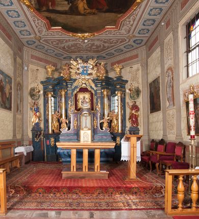 Zdjęcie nr 2: Nastawa ołtarzowa architektoniczna, trójosiowa, jednokondygnacyjna, ustawiona na wysokim cokole. Ołtarz wolnostojący, odsunięty od retabulum, drewniany, sarkofagowy z drewnianą mensą, na nim ustawione tabernakulum. Nastawa opasująca trójbocznie zamknięte prezbiterium, osie wydzielone czterema parami pilastrów o trzonach dekorowanych rocaille'em, przed którymi stoją cztery kolumny o kapitelach kompozytowych i trzonach z dekoracją geometryczną, dźwigających imposty. W polu środkowym nisza w formie stojącego prostokąta zamkniętego łukiem segmentowym nadwieszonym z uskokiem, ujęta profilowaną ramą dekorowaną rocaille'em z dużo mniejszym obrazem Matki Boskiej Nieustającej Pomocy w osobnej ramie na czerwonym tle. Osie boczne przeprute oknami w formie stojącego prostokąta zamkniętego łukiem segmentowym, na ich tle stoją figury aniołów. Nad polem głównym medalion z obłoków i uskrzydlonych główek anielskich z gołębicą Ducha Świętego w glorii promienistej. Na belkowaniu, na osi wewnętrznych impostów dwa siedzące na obłokach putta, na osi zewnętrznych rokokowe wazony. Nastawa flankowana dwoma przyściennymi cokołami, na których stoją figury św. Piotra i św. Pawła. Struktura architektoniczna polichromowana na sposób imitujący niebiesko-białą marmoryzację, trzony pilastrów fioletową. Ornamentyka, profile, kolumny i gloria pozłacane i posrebrzane. 
 





