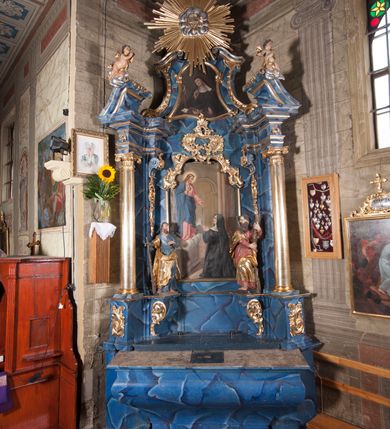 Zdjęcie nr 2: Nastawa architektoniczna, jednoosiowa, jednokondygnacyjna ze zwieńczeniem, ustawiona na cokole. Ołtarz drewniany, sarkofagowy, zwężający się ku dołowi, z drewnianą mensą i kamiennym portatylem. Nastawa ujęta parą półfilarów i stojącą przed nimi parą kolumn o kapitelach jońskich, dźwigających imposty i przerwany falisty przyczółek, na którym siedzą putta na obłokach. Po wewnętrznej stronie półfilarów konsole, na których stoją figury św. Judy Tadeusza i św. Andrzeja, nad nimi konsole podtrzymujące imposty, dekorowane w partii trzonów rocaille&#039;em. W polu głównym płycina w formie stojącego prostokąta zamkniętego łukiem półkolistym nadwieszonym, ujęta ramą dekorowana rocaille&#039;em w partii łuku, z obrazem wizji św. Małgorzaty Marii Alacoque, nad łukiem rocaille. Zwieńczenie w formie zbliżonej do stojącego prostokąta, flankowane spływami wolutowymi, zamknięte dwoma fragmentami wolutowego gzymsu oraz glorią promienistą z monogramem IHS na tle obłoków w centrum. W polu obraz św. Kingi w formie zbliżonej do zwieńczenia, ujęty ramą. Struktura ołtarza polichromowana na sposób naśladujący marmoryzację w kolorze niebiesko-białym, kolumny, ornamenty i profile pozłocone.