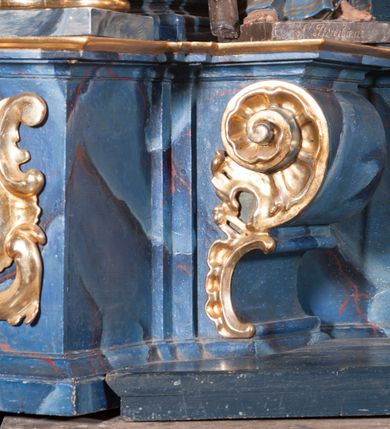 Zdjęcie nr 5: Nastawa architektoniczna, jednoosiowa, jednokondygnacyjna ze zwieńczeniem, ustawiona na cokole. Ołtarz drewniany, sarkofagowy, zwężający się ku dołowi, z drewnianą mensą i kamiennym portatylem. Nastawa ujęta parą półfilarów i stojącą przed nimi parą kolumn o kapitelach jońskich, dźwigających imposty i przerwany falisty przyczółek, na którym siedzą putta na obłokach. Po wewnętrznej stronie półfilarów konsole, na których stoją figury św. Judy Tadeusza i św. Andrzeja, nad nimi konsole podtrzymujące imposty, dekorowane w partii trzonów rocaille&#039;em. W polu głównym płycina w formie stojącego prostokąta zamkniętego łukiem półkolistym nadwieszonym, ujęta ramą dekorowana rocaille&#039;em w partii łuku, z obrazem wizji św. Małgorzaty Marii Alacoque, nad łukiem rocaille. Zwieńczenie w formie zbliżonej do stojącego prostokąta, flankowane spływami wolutowymi, zamknięte dwoma fragmentami wolutowego gzymsu oraz glorią promienistą z monogramem IHS na tle obłoków w centrum. W polu obraz św. Kingi w formie zbliżonej do zwieńczenia, ujęty ramą. Struktura ołtarza polichromowana na sposób naśladujący marmoryzację w kolorze niebiesko-białym, kolumny, ornamenty i profile pozłocone.