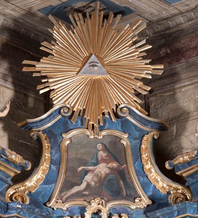 Zdjęcie nr 11: Nastawa architektoniczna, jednoosiowa, jednokondygnacyjna ze zwieńczeniem, ustawiona na cokole. Ołtarz drewniany, sarkofagowy, zwężający się ku dołowi, z drewnianą mensą i kamiennym portatylem. Nastawa ujęta parą półfilarów i stojącą przed nimi parą kolumn o kapitelach jońskich, dźwigających imposty i przerwany, falisty przyczółek, na którym siedzą dwa putta na obłokach. Po wewnętrznej stronie półfilarów w partii cokołu konsole, na których stoją figury św. Anny i św. Joachima, ponad nimi konsole podtrzymujące imposty, dekorowane w partii trzonów rocaille'em. W polu głównym płycina w formie stojącego prostokąta zamkniętego łukiem segmentowym nadwieszonym, ujęta ramą dekorowaną rocaille'em w partii łuku, z obrazem Matki Boskiej z Dzieciątkiem i św. Dominikiem, nad łukiem rocaille. Zwieńczenie w formie zbliżonej do stojącego prostokąta, flankowane spływami wolutowymi, zamknięte dwoma fragmentami wolutowego gzymsu oraz glorią promienistą z okiem Opatrzności w centrum. W polu obraz o formie zbliżonej do zwieńczenia przedstawiający Pietę, ujęty ramą. Struktura ołtarza polichromowana na sposób naśladujący marmoryzację w kolorze niebiesko-białym, kolumny, ornamenty i profile pozłocone.