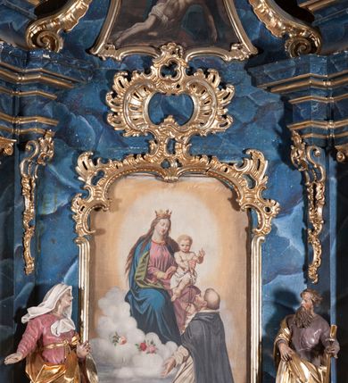 Zdjęcie nr 2: Nastawa architektoniczna, jednoosiowa, jednokondygnacyjna ze zwieńczeniem, ustawiona na cokole. Ołtarz drewniany, sarkofagowy, zwężający się ku dołowi, z drewnianą mensą i kamiennym portatylem. Nastawa ujęta parą półfilarów i stojącą przed nimi parą kolumn o kapitelach jońskich, dźwigających imposty i przerwany, falisty przyczółek, na którym siedzą dwa putta na obłokach. Po wewnętrznej stronie półfilarów w partii cokołu konsole, na których stoją figury św. Anny i św. Joachima, ponad nimi konsole podtrzymujące imposty, dekorowane w partii trzonów rocaille&#039;em. W polu głównym płycina w formie stojącego prostokąta zamkniętego łukiem segmentowym nadwieszonym, ujęta ramą dekorowaną rocaille&#039;em w partii łuku, z obrazem Matki Boskiej z Dzieciątkiem i św. Dominikiem, nad łukiem rocaille. Zwieńczenie w formie zbliżonej do stojącego prostokąta, flankowane spływami wolutowymi, zamknięte dwoma fragmentami wolutowego gzymsu oraz glorią promienistą z okiem Opatrzności w centrum. W polu obraz o formie zbliżonej do zwieńczenia przedstawiający Pietę, ujęty ramą. Struktura ołtarza polichromowana na sposób naśladujący marmoryzację w kolorze niebiesko-białym, kolumny, ornamenty i profile pozłocone.