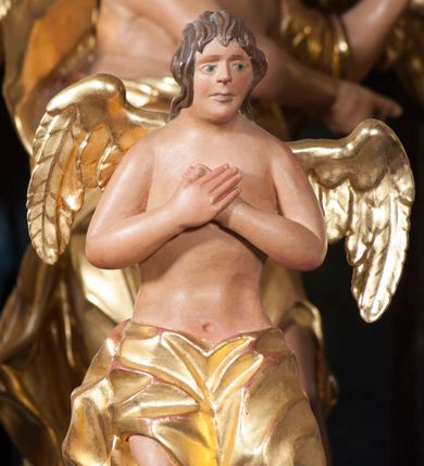 Zdjęcie nr 7: Tabernakulum w formie pozłoconej, prostopadłościennej skrzynki z metalowymi, pozłoconymi i posrebrzonymi drzwiczkami w kształcie stojącego prostokąta zamkniętego łukiem półkolistym z symbolami eucharystycznymi – kielichem z hostią, kłosami zbóż i winnym gronem. Nad tabernakulum tron wystawienia w formie obrotowej niszy o wypukłym licu w architektonicznej obudowie, ujęty spływami wolutowymi, na których znajdują się klęczące figury aniołów, opadającymi na profilowany cokół flankujący tabernakulum. Obrotowa nisza ujęta ramą, flankowana parą pilastrów dźwigających gzyms w formie łuku półkolistego, ujęta ornamentem roślinnym. Pośrodku na gzymsie baranek apokaliptyczny leżący na księdze, na krawędziach gzymsu na cokolikach dwie niewielkie figurki adorujących aniołków. Struktura polichromowana w sposób naśladujący marmoryzację w kolorze fioletowym, z niebieskimi detalami, tabernakulum pozłocone i posrebrzone, ornamentyka i profile pozłocone, figury o naturalnej karnacji i pozłoconych szatach. 

