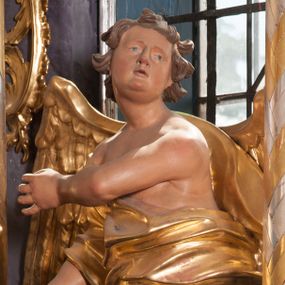 Zdjęcie nr 1: Dwie rzeźby aniołów ustawione są na niewielkich podstawach. Obie figury o układzie ciała w lustrzanym odbiciu względem siebie, zwrócone są frontalnie, w kontrapoście, z głowami skierowanymi w stronę pola głównego ołtarza oraz rękami wyciągniętymi w przeciwną stronę. Twarze mają pociągłe, o młodzieńczych rysach, blisko siebie osadzonych oczach, lekko garbatych nosach, rozchylonych ustach i wystających brodach, okolone ekspresyjnie rozwianymi, krótkimi włosami, rzeźbionymi w pojedyncze pasma. Anioły ubrane są w pozłocone, przylegające do ciała tuniki z jednym rękawem, odsłaniające część torsu i jedną nogę. Obie figury posiadają pozłocone, złożone skrzydła. Polichromia ciała naturalistyczna. 

