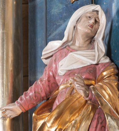 Zdjęcie nr 1: Rzeźba drążona z tyłu, ustawiona na niskiej podstawie z inskrypcją „S(ancta) Anna”. Święta w kontrapoście, zwrócona w trzech czwartych w prawo, z głową skierowaną w lewo. Lewą rękę wyciąga w przód, prawą w bok. Jej twarz ma starcze rysy, lekko garbaty nos, oczy usytuowane blisko siebie oraz pełne, rozchylone usta. Ubrana jest w różową tunikę o pozłoconym wzorze i lamówce, przewiązaną wstęgą w pasie, pozłocony płaszcz zawiązany diagonalnie wokół postaci i zarzucony na lewe ramię, na głowie ma biały welon. Polichromia ciała naturalistyczna. 

