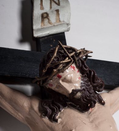 Zdjęcie nr 8: Figura umarłego Chrystusa jest przybita do krzyża o prostych ramionach trzema gwoździami. Ciało w dużym zwisie, o układzie ramion przyjmujących kształt litery „V” oraz dłoniach w geście błogosławieństwa. Głowa opada bezwładnie na prawy bark. Nogi są ugięte w kolanach, a stopy skrzyżowane w układzie prawa na lewą. Twarz Chrystusa jest pociągła, o prostym nosie, zamkniętych oczach i uniesionych brwiach, okolona silnie kręconą brodą oraz kręconymi włosami opadającymi na ramiona. Na głowie korona cierniowa. Ciało silnie umięśnione o wyraźnie podkreślonych żebrach klatki piersiowej. Perizonium krótkie, zawieszone na sznurze, odsłaniające prawe biodro, ze zwisem tkaniny na prawym boku. Ciało polichromowane w kolorze naturalistycznym z zaznaczonymi śladami męki, korona cierniowa i perizonium pozłocone. Pionowa belka krzyża zwieńczona tabliczką z napisem „IN / RI”.
