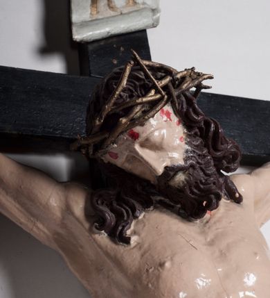 Zdjęcie nr 7: Figura umarłego Chrystusa jest przybita do krzyża o prostych ramionach trzema gwoździami. Ciało w dużym zwisie, o układzie ramion przyjmujących kształt litery „V” oraz dłoniach w geście błogosławieństwa. Głowa opada bezwładnie na prawy bark. Nogi są ugięte w kolanach, a stopy skrzyżowane w układzie prawa na lewą. Twarz Chrystusa jest pociągła, o prostym nosie, zamkniętych oczach i uniesionych brwiach, okolona silnie kręconą brodą oraz kręconymi włosami opadającymi na ramiona. Na głowie korona cierniowa. Ciało silnie umięśnione o wyraźnie podkreślonych żebrach klatki piersiowej. Perizonium krótkie, zawieszone na sznurze, odsłaniające prawe biodro, ze zwisem tkaniny na prawym boku. Ciało polichromowane w kolorze naturalistycznym z zaznaczonymi śladami męki, korona cierniowa i perizonium pozłocone. Pionowa belka krzyża zwieńczona tabliczką z napisem „IN / RI”.
