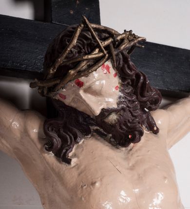 Zdjęcie nr 9: Figura umarłego Chrystusa jest przybita do krzyża o prostych ramionach trzema gwoździami. Ciało w dużym zwisie, o układzie ramion przyjmujących kształt litery „V” oraz dłoniach w geście błogosławieństwa. Głowa opada bezwładnie na prawy bark. Nogi są ugięte w kolanach, a stopy skrzyżowane w układzie prawa na lewą. Twarz Chrystusa jest pociągła, o prostym nosie, zamkniętych oczach i uniesionych brwiach, okolona silnie kręconą brodą oraz kręconymi włosami opadającymi na ramiona. Na głowie korona cierniowa. Ciało silnie umięśnione o wyraźnie podkreślonych żebrach klatki piersiowej. Perizonium krótkie, zawieszone na sznurze, odsłaniające prawe biodro, ze zwisem tkaniny na prawym boku. Ciało polichromowane w kolorze naturalistycznym z zaznaczonymi śladami męki, korona cierniowa i perizonium pozłocone. Pionowa belka krzyża zwieńczona tabliczką z napisem „IN / RI”.
