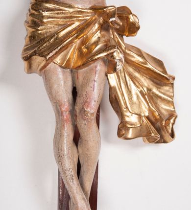 Zdjęcie nr 17: Figura umarłego Chrystusa przybita trzema gwoździami do prostego krzyża. Ciało o horyzontalnie rozłożonych ramionach, z głową opadającą na prawy bark, lewą nogą ugiętą w kolanie, prawą wyprostowaną oraz stopami skrzyżowanymi w układzie prawa na lewą. Twarz szczupła, z nosem o ostrym profilu, zamkniętych oczach i rozchylonych ustach, okolona jest rozdwajającą się brodą oraz silnie kręconymi włosami opadającymi na plecy i na prawe ramię. Na głowie szeroka korona cierniowa. Ciało szczupłe, smukłe, miękko modelowane, o podkreślonej muskulaturze ramion i ud oraz zaznaczonych delikatnie żebrach i mostku klatki piersiowej. Perizonium krótkie, silnie drapowane, zawiązane na sznurze, odsłaniające fragment lewego biodra z silnie rozwianym zwisem tkaniny na lewym boku. Polichromia ciała w kolorze naturalistycznym z zaznaczonymi śladami męki, korona cierniowa i perizonium pozłocone. Na zakończeniu pionowej belki krzyża banderola z napisem „I.N. / R.I.”

