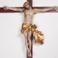 Zdjęcie nr 1: Figura umarłego Chrystusa przybita trzema gwoździami do prostego krzyża. Ciało o horyzontalnie rozłożonych ramionach, z głową opadającą na prawy bark, lewą nogą ugiętą w kolanie, prawą wyprostowaną oraz stopami skrzyżowanymi w układzie prawa na lewą. Twarz szczupła, z nosem o ostrym profilu, zamkniętych oczach i rozchylonych ustach, okolona jest rozdwajającą się brodą oraz silnie kręconymi włosami opadającymi na plecy i na prawe ramię. Na głowie szeroka korona cierniowa. Ciało szczupłe, smukłe, miękko modelowane, o podkreślonej muskulaturze ramion i ud oraz zaznaczonych delikatnie żebrach i mostku klatki piersiowej. Perizonium krótkie, silnie drapowane, zawiązane na sznurze, odsłaniające fragment lewego biodra z silnie rozwianym zwisem tkaniny na lewym boku. Polichromia ciała w kolorze naturalistycznym z zaznaczonymi śladami męki, korona cierniowa i perizonium pozłocone. Na zakończeniu pionowej belki krzyża banderola z napisem „I.N. / R.I.”

