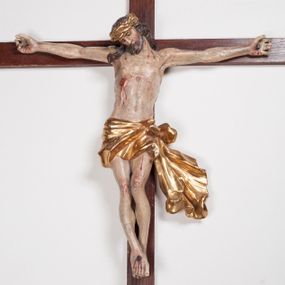 Zdjęcie nr 1: Figura umarłego Chrystusa przybita trzema gwoździami do prostego krzyża. Ciało o horyzontalnie rozłożonych ramionach, z głową opadającą na prawy bark, lewą nogą ugiętą w kolanie, prawą wyprostowaną oraz stopami skrzyżowanymi w układzie prawa na lewą. Twarz szczupła, z nosem o ostrym profilu, zamkniętych oczach i rozchylonych ustach, okolona jest rozdwajającą się brodą oraz silnie kręconymi włosami opadającymi na plecy i na prawe ramię. Na głowie szeroka korona cierniowa. Ciało szczupłe, smukłe, miękko modelowane, o podkreślonej muskulaturze ramion i ud oraz zaznaczonych delikatnie żebrach i mostku klatki piersiowej. Perizonium krótkie, silnie drapowane, zawiązane na sznurze, odsłaniające fragment lewego biodra z silnie rozwianym zwisem tkaniny na lewym boku. Polichromia ciała w kolorze naturalistycznym z zaznaczonymi śladami męki, korona cierniowa i perizonium pozłocone. Na zakończeniu pionowej belki krzyża banderola z napisem „I.N. / R.I.”

