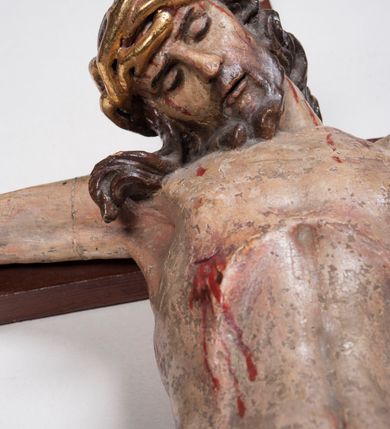 Zdjęcie nr 7: Figura umarłego Chrystusa przybita trzema gwoździami do prostego krzyża. Ciało o horyzontalnie rozłożonych ramionach, z głową opadającą na prawy bark, lewą nogą ugiętą w kolanie, prawą wyprostowaną oraz stopami skrzyżowanymi w układzie prawa na lewą. Twarz szczupła, z nosem o ostrym profilu, zamkniętych oczach i rozchylonych ustach, okolona jest rozdwajającą się brodą oraz silnie kręconymi włosami opadającymi na plecy i na prawe ramię. Na głowie szeroka korona cierniowa. Ciało szczupłe, smukłe, miękko modelowane, o podkreślonej muskulaturze ramion i ud oraz zaznaczonych delikatnie żebrach i mostku klatki piersiowej. Perizonium krótkie, silnie drapowane, zawiązane na sznurze, odsłaniające fragment lewego biodra z silnie rozwianym zwisem tkaniny na lewym boku. Polichromia ciała w kolorze naturalistycznym z zaznaczonymi śladami męki, korona cierniowa i perizonium pozłocone. Na zakończeniu pionowej belki krzyża banderola z napisem „I.N. / R.I.”

