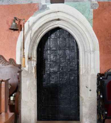 Zdjęcie nr 1: Ostrołukowy portal do zakrystii z węgarami do wysokości 35 cm sfazowanymi, wyżej ściętymi, a w górnej połowie bogato profilowany. Wypełniają go drzwi płytowe, prostokątne, zamknięte łukiem ostrym. Drewniane, okute blachą i kratą z metalowych listew, z zamkiem nakładanym od strony zakrystii i parą wrzeciądzów. W środkowych płytach dwa herby: Leszczyc (Bróg) i Niesobia (?).