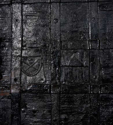 Zdjęcie nr 2: Ostrołukowy portal do zakrystii z węgarami do wysokości 35 cm sfazowanymi, wyżej ściętymi, a w górnej połowie bogato profilowany. Wypełniają go drzwi płytowe, prostokątne, zamknięte łukiem ostrym. Drewniane, okute blachą i kratą z metalowych listew, z zamkiem nakładanym od strony zakrystii i parą wrzeciądzów. W środkowych płytach dwa herby: Leszczyc (Bróg) i Niesobia (?).