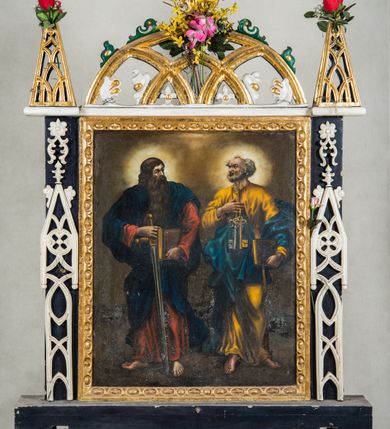 Zdjęcie nr 2: Feretron procesyjny dwustronny, na drewnianej, prostopadłościennej podstawie dekorowanej z jednej strony laskowaniem, z otworami na drążki. Obrazy w kształcie stojącego prostokąta, ujęte po bokach czarnymi listwami pokrytymi białą dekoracją maswerkową. Zwieńczenie ażurowe w formie łuku w „ośli grzbiet”, flankowane trójkątnymi szczytami, które są ażurowe i wypełnione laskowaniem.
 Na obrazie z przedstawieniem Koronacji Marii pośrodku kompozycji ukazana Madonna klęczącą na półksiężycu zwróconym do dołu; po bokach Chrystus i Bóg Ojciec trzymający koronę nad jej głową, powyżej gołębica Ducha Świętego. Maria ukazana frontalnie, klęczy na lewym kolanie, ręce składa na piersi, głowę skręca delikatnie na prawo. Twarz owalna o delikatnych, dziewczęcych rysach okolona długimi, falowanymi, brązowymi włosami opadającymi na plecy. Ubrana w różową suknię opadającą fałdami na półksiężyc, lamowaną pod szyją złotą taśmą oraz niebieski płaszcz, który przerzucony przez lewe ramię rozwiewa się za jej plecami. Po lewej stronie Chrystus ukazany z profilu, w dynamicznym wykroku, prawą ręką podtrzymuje koronę, lewą krzyż. Twarz okalają ciemne, opadające na plecy, falowane włosy i krótka broda. Okryty dwoma bogato fałdującymi się, rozwianymi płaszczami: czerwony otula nogi i plecy, rozwiewając się za plecami, granatowy przerzucony jest przez lewą rękę, rozwiewa się w dolnej partii, tworząc tło dla nóg. Po prawej stronie Bóg Ojciec siedzący frontalnie ponad globem ziemskim pochyla się w stronę Marii. W prawej ręce trzyma koronę, lewą przytrzymuje oparte na kolanie berło. Twarz okalają siwe, falowane włosy i długa broda. Postać ubrana w jasnobrązową suknię z szerokimi rękawami oraz zielony, lamowany płaszcz. Tło kompozycji wypełniają jasnobrązowe obłoki rozświetlone w przestrzeni między czterema postaciami. 
Na drugim obrazie apostołowie św. Piotr i św. Paweł ukazani frontalnie, całopostaciowo, z głowami zwróconymi do siebie. Po prawej stronie św. Piotr, który w prawej ręce złożonej na piersi trzyma klucze, lewą, opuszczoną podtrzymuje zamkniętą księgę. Twarz o wyrazistych rysach, wysokim czole, ściągniętych brwiach i wydatnych kościach policzkowych okalają pukle siwych włosów i krótka broda. Święty ubrany w długą, żółtą tunikę i ciemnoniebieski płaszcz okrywający biodra i lewe ramię. Po lewej stronie św. Paweł, który prawą ręką przytrzymuje oparty ostrzem o ziemię miecz, lewą księgę. Twarz o podobnych wyrazistych rysach okalają długa ciemna broda i grube, falowane włosy. Święty ubrany w czerwoną tunikę i granatowy płaszcz okrywający ramiona i biodra, opadający z tyłu do ziemi. Fałdy szat obydwu postaci obfite, miękkie. Spod szat wystają bose stopy. Wokół głów świetliste nimby. Tło kompozycji jednolite, jasnobrązowe. 
Ramy obrazów zdobione ornamentem geometrycznym imitującym rauty i kaboszony.