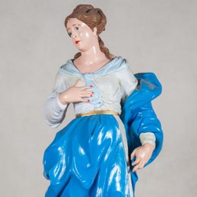 Zdjęcie nr 1: Podstawa feretronu w formie dwóch uproszczonych wolut z otworami na drążki, na płaskich podstawach. Na nich pełnoplastyczna figura Matki Boskiej w typie Niepokalanie Poczętej, stojąca na globie ziemskim, depcząca oplatającego go węża, który trzyma w paszczy jabłko. Maria ukazana w kontrapoście, z prawą nogą wysuniętą do przodu, lewą odwiedzioną, zgiętą w kolanie; prawą rękę składa na piersi, lewą, opuszczoną przytrzymuje płaszcz. Głowa przechylona w prawą stronę; twarz owalna z szeroko otworzonymi, niebieskimi oczami poniżej uniesionych brwi, z prostym nosem i drobnymi, ciemnoczerwonymi ustami, otoczona brązowymi, upiętymi w kok włosami, z wolnymi pasmami spływającymi na lewe ramię i plecy. Madonna ubrana w białą suknię z szerokim  jasnoniebieskim kołnierzem wiązanym na dekolcie, przepasaną złotym paskiem oraz błękitny płaszcz, który układając się w grube fałdy otacza jej lewą rękę, przechodzi przez prawe biodro i jest zatknięty z przodu za pasek.