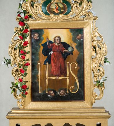 Zdjęcie nr 7: Feretron dwustronny, z podstawą prostopadłościenną, wyciętą od dołu, z otworami na drążki. Na podstawie obrazy z przedstawieniem Matki Boskiej z Dzieciątkiem oraz Dzieciątka w typie Emmanuela ujęte drewnianą ramą. Po bokach i od góry ażurowe obramienia utworzone ze splotu ornamentu małżowinowo-chrząstkowego. W zwieńczeniu kartusz z owalnym polem z reprodukcjami „Tondo Doni&quot; Michała Anioła i na odwrociu „Madonna z Księgą&quot; Rafaela Santi. 
Matka Boska z Dzieciątkiem w typie Matki Boskiej Śnieżnej została ukazana w trzech czwartych, z Dzieciątkiem na lewym ramieniu i skrzyżowanymi dłońmi, w lewej trzyma białą chustę. Maria ma pociągłą twarz o wyrazistych rysach: oczy migdałowate, nos prosty, szeroki, usta niewielkie. Jest ubrana w białą suknię lamowaną pod szyją złotą taśmą; granatowy płaszcz z brązową podszewką okrywający głowę i ramiona, z krzyżem równoramiennym na wysokości czoła i sześcioramienną gwiazdą na prawym boku. Dzieciątko zwrócone w prawą stronę, prawą rączkę unosi w geście błogosławieństwa, w lewej trzyma zamkniętą księgę. Okrągłą twarz o ostrych rysach okalają pukle ciemnych włosów. Dzieciątko ubrane w jasnożółtą sukienkę obwiedzioną pod szyją złotą taśmą i brązowy płaszcz otulający nogi, na stopach sandały. Wokół głów postaci żółte, okrągłe nimby. Tło obrazu jednolite, ciemnobrązowe.  
Na drugim obrazie przedstawiono Dzieciątko Jezus w typie Emmanuela stojące na hierogramie IHS . Ukazane frontalnie, z prawą ręką uniesioną w geście błogosławieństwa, w lewej trzyma glob ziemski  zwieńczony krzyżem(jabłko królewskie). Twarz Dzieciątka o mało zindywidualizowanych, nieco „postarzonych” rysach, okrągłej twarzy, z wyraźnie zaznaczonym małym podbródkiem okalają jasne, falowane włosy, wokół głowy jasny nimb. Tunika czerwona, lamowana pod szyją i przy rękawach złotą taśmą, przepasana białą szarfą, której końce rozwiewają się przy prawym biodrze oraz granatowy, rozwiany płaszcz widoczny za plecami. Postać jest ukazana na żółtym tle otoczonym  z trzech stron ciemnymi obłokami i z uskrzydlonymi główkami aniołków: dwie symetrycznie po obu stronach Dzieciątka i dwie na dole. 