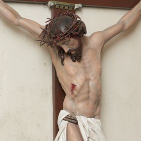 Zdjęcie nr 1: Pełnoplastyczna, polichromowana figura Chrystusa na krzyżu. Sylwetka zmarłego jest smukła, o naturalnej karnacji,  z wyraźnie zaznaczoną muskulaturą i układem kostnym. Ramiona uniesione do góry tworzą łuk, nogi są lekko ugięte w kolanach. Głowa opada nisko na prawe ramię, twarz pociągła, oczy zamknięte, nos szpiczasty o prostym profilu, usta lekko otwarte. Na prawe ramię spływa pasmo długich włosów, krótka broda dzieli się na dwa pukle. Na głowie korona cierniowa, biodra przewiązane białym, krótkim perizonium podtrzymywanym podwójnym sznurem, opadające pionowymi fałdami na prawy bok. Na ciele Chrystusa widoczne są ślady męki: przebity bok, dłonie oraz stopy. Nad głową titulus z napisem „INRI”.
