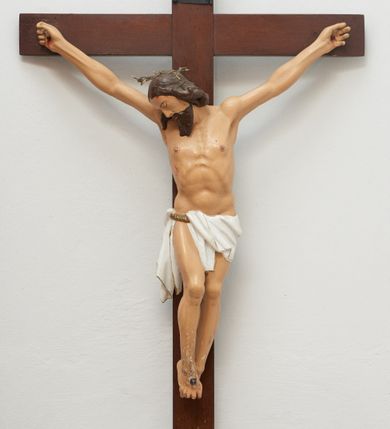 Zdjęcie nr 1: Pełnoplastyczna figura Chrystusa na prostym krzyżu. Sylwetka zmarłego z wyraźnie zarysowaną muskulaturą, ramiona uniesione do góry tworzą łuk, palce dłoni zgięte, nogi lekko ugięte w kolanach. Głowa opada na prawe ramię, twarz pociągła pozbawiona cech indywidualnych, oczy i usta zamknięte. Na prawy bark spływa pukiel długich włosów, broda długa. Na głowie cienka zielono-brązowa korona cierniowa. Perizonium krótkie, białe ze złotą lamówką, podtrzymywane sznurem, opadające kaskadami na prawy bok. Na ciele Chrystusa czerwoną farbą zaznaczone ślady męki: przebity bok, dłonie i  skrzyżowane stopy w miejscach przebicia gwoździami. Nad głową titulus z napisem „INRI”. W partiach ciała polichromia naturalistyczna.