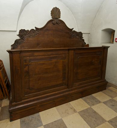 Zdjęcie nr 1: Ława kolatorska na prostopadłościennej podstawie, przedpiersie z gzymsem, podzielone trzema pilastrami pomiędzy którymi prostokątne płyciny. Zaplecek o symetrycznym, wklęsło-wypukłym brzegu zdobiony ornamentem rocaille'owym i muszlami, zwieńczony dwoma stykającymi się wolutami i podwójną  muszlą.