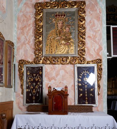 Zdjęcie nr 1: Ołtarz składający się z obrazu Matki Boskiej w prostokątnym, ażurowym obramieniu utworzonym z akantu mięsistego, zwieńczonym rzeźbionym monogramem Marii i umieszczonych poniżej dwóch prostokątnych gablot z wotami, których zewnętrzne górne narożniki ujęto podobną wicią. Mensa drewniana z portatylem. Antepedium w kształcie leżącego prostokąta, zakończone profilowanym gzymsem, ujęte ornamentem sznurowym w blendach. W polu frontowym trzy prostokątne płyciny wypełnione rombami otoczonymi winną latoroślą. W środkowym rombie istota apokaliptyczna – uskrzydlony byk z banderolą, boczne wypełniają czteroliście. Na bocznej ścianie mensy kwadratowa płycina z dekoracją w formie winnej latorośli. Na mensie listwa z rzeźbionym maswerkiem oraz  prostopadłościenne tabernakulum ze ścianką frontową w kształcie ujmującej drzwi arkady złożonej z profilowanego łuku nadwieszonego, podtrzymywanego przez pilastry; na płaskich fragmentach belkowania ustawiono prostopadłościany z plakietami ornamentalnymi.
Struktura antepedium w kolorze bejcowanego drewna, nisze malowane na granatowo, ramy i ornamenty złocone.
