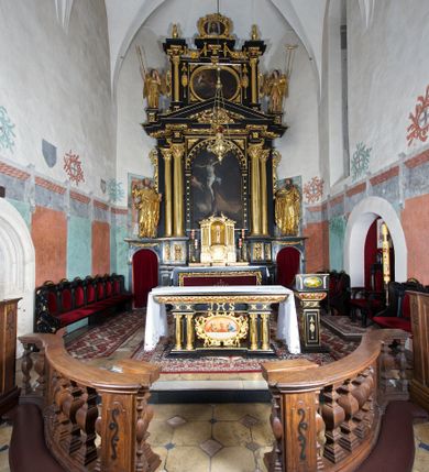 Zdjęcie nr 6: Ołtarz architektoniczny, jednoosiowy, dwukondygnacyjny, z bramkami, na cokole. Pierwsza kondygnacja ujęta parą pilastrów za dwiema parami gładkich kolumn o kapitelach kompozytowych, dźwigających imposty, z gzymsem wyłamanym w partii podpór. Środkowa para wysunięta przed lico ołtarza, zwieńczona trójkątnym przyczółkiem z rzeźbą przedstawiającą Boga Ojca w obłokach. Pole środkowe w formie arkady z obrazem Ukrzyżowania. Kondygnacja ujęta uszami utworzonymi z ornamentu małżowinowo-chrząstkowego. Na bramkach figury św. Piotra i św. Pawła. Druga kondygnacja w formie leżącego prostokąta, ujęta parą pilastrów i stojącą przed nimi parą gładkich kolumn o kapitelach kompozytowych, dźwigających imposty. Kondygnacja flankowana dwiema figurami aniołów stojących na postumentach. Pole obrazowe z przedstawieniem Chrystusa w Ogrójcu w formie leżącego owalu w prostokątnej płycinie. Zwieńczenie przyjmujące kształt impostu dźwigającego na szerokim gzymsie owalny kartusz ujęty ornamentem małżowinowo-chrząstkowym z przedstawieniem Veraicon. Nastawa pokryta bogatą dekoracją ornamentalną. W partii cokołów płyciny z ornamentem małżowinowo-chrząstkowym, w wewnętrznych dodatkowo główki anielskie oraz girlandy utworzone z tkaniny nad arkadami bramek. Czoło arkady pola środkowego dekorowane rozetami, w ościeżach bocznych małżowina, w podłuczu kasetony z rozetami. W przyłuczu arkady ornament roślinny. W impostach, w partii fryzu rozety, powyżej ażurowy ornament małżowinowo-chrząstkowy dekoruje podstawę gzymsu. Przyczółek ozdobiony małżowiną. W drugiej kondygnacji owalna rama obrazu przyjmuje postać wieńca laurowego dekorowanego kartuszami z kaboszonami. W narożach płyciny małżowina. Pole ujęte festonami utworzonymi z tkaniny, owoców i kwiatów. Fryz impostów dekorowany analogicznie jak w pierwszej kondygnacji. Na fragmentach belkowania wazony. Odcinki gzymsu połączone girlandą z tkaniny z pękiem owoców i kwiatów. Kondygnacja ujęta uszami z ornamentu małżowinowo-chrząstkowego. 
Ołtarz kamienny z drewnianą obudową i mensą z portatylem. Antepedium w formie leżącego prostokąta, ujęte ornamentalną ramą z motywem akantu. W polu purpurowa tkanina z haftowanym monogramem IHS. Nastawa polichromowana na kolor czarny ze złoconymi kolumnami, detalami architektonicznymi i ornamentyką.