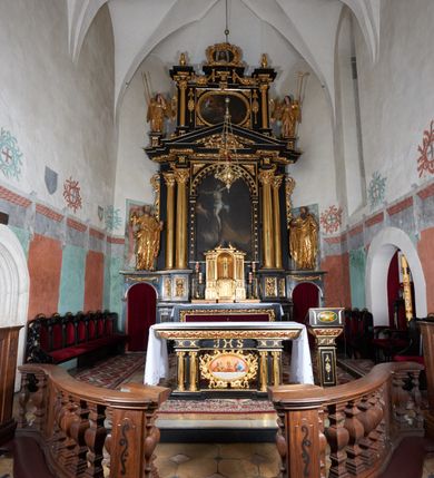 Zdjęcie nr 7: Ołtarz architektoniczny, jednoosiowy, dwukondygnacyjny, z bramkami, na cokole. Pierwsza kondygnacja ujęta parą pilastrów za dwiema parami gładkich kolumn o kapitelach kompozytowych, dźwigających imposty, z gzymsem wyłamanym w partii podpór. Środkowa para wysunięta przed lico ołtarza, zwieńczona trójkątnym przyczółkiem z rzeźbą przedstawiającą Boga Ojca w obłokach. Pole środkowe w formie arkady z obrazem Ukrzyżowania. Kondygnacja ujęta uszami utworzonymi z ornamentu małżowinowo-chrząstkowego. Na bramkach figury św. Piotra i św. Pawła. Druga kondygnacja w formie leżącego prostokąta, ujęta parą pilastrów i stojącą przed nimi parą gładkich kolumn o kapitelach kompozytowych, dźwigających imposty. Kondygnacja flankowana dwiema figurami aniołów stojących na postumentach. Pole obrazowe z przedstawieniem Chrystusa w Ogrójcu w formie leżącego owalu w prostokątnej płycinie. Zwieńczenie przyjmujące kształt impostu dźwigającego na szerokim gzymsie owalny kartusz ujęty ornamentem małżowinowo-chrząstkowym z przedstawieniem Veraicon. Nastawa pokryta bogatą dekoracją ornamentalną. W partii cokołów płyciny z ornamentem małżowinowo-chrząstkowym, w wewnętrznych dodatkowo główki anielskie oraz girlandy utworzone z tkaniny nad arkadami bramek. Czoło arkady pola środkowego dekorowane rozetami, w ościeżach bocznych małżowina, w podłuczu kasetony z rozetami. W przyłuczu arkady ornament roślinny. W impostach, w partii fryzu rozety, powyżej ażurowy ornament małżowinowo-chrząstkowy dekoruje podstawę gzymsu. Przyczółek ozdobiony małżowiną. W drugiej kondygnacji owalna rama obrazu przyjmuje postać wieńca laurowego dekorowanego kartuszami z kaboszonami. W narożach płyciny małżowina. Pole ujęte festonami utworzonymi z tkaniny, owoców i kwiatów. Fryz impostów dekorowany analogicznie jak w pierwszej kondygnacji. Na fragmentach belkowania wazony. Odcinki gzymsu połączone girlandą z tkaniny z pękiem owoców i kwiatów. Kondygnacja ujęta uszami z ornamentu małżowinowo-chrząstkowego. 
Ołtarz kamienny z drewnianą obudową i mensą z portatylem. Antepedium w formie leżącego prostokąta, ujęte ornamentalną ramą z motywem akantu. W polu purpurowa tkanina z haftowanym monogramem IHS. Nastawa polichromowana na kolor czarny ze złoconymi kolumnami, detalami architektonicznymi i ornamentyką.