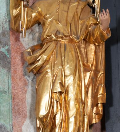 Zdjęcie nr 11: Ołtarz architektoniczny, jednoosiowy, dwukondygnacyjny, z bramkami, na cokole. Pierwsza kondygnacja ujęta parą pilastrów za dwiema parami gładkich kolumn o kapitelach kompozytowych, dźwigających imposty, z gzymsem wyłamanym w partii podpór. Środkowa para wysunięta przed lico ołtarza, zwieńczona trójkątnym przyczółkiem z rzeźbą przedstawiającą Boga Ojca w obłokach. Pole środkowe w formie arkady z obrazem Ukrzyżowania. Kondygnacja ujęta uszami utworzonymi z ornamentu małżowinowo-chrząstkowego. Na bramkach figury św. Piotra i św. Pawła. Druga kondygnacja w formie leżącego prostokąta, ujęta parą pilastrów i stojącą przed nimi parą gładkich kolumn o kapitelach kompozytowych, dźwigających imposty. Kondygnacja flankowana dwiema figurami aniołów stojących na postumentach. Pole obrazowe z przedstawieniem Chrystusa w Ogrójcu w formie leżącego owalu w prostokątnej płycinie. Zwieńczenie przyjmujące kształt impostu dźwigającego na szerokim gzymsie owalny kartusz ujęty ornamentem małżowinowo-chrząstkowym z przedstawieniem Veraicon. Nastawa pokryta bogatą dekoracją ornamentalną. W partii cokołów płyciny z ornamentem małżowinowo-chrząstkowym, w wewnętrznych dodatkowo główki anielskie oraz girlandy utworzone z tkaniny nad arkadami bramek. Czoło arkady pola środkowego dekorowane rozetami, w ościeżach bocznych małżowina, w podłuczu kasetony z rozetami. W przyłuczu arkady ornament roślinny. W impostach, w partii fryzu rozety, powyżej ażurowy ornament małżowinowo-chrząstkowy dekoruje podstawę gzymsu. Przyczółek ozdobiony małżowiną. W drugiej kondygnacji owalna rama obrazu przyjmuje postać wieńca laurowego dekorowanego kartuszami z kaboszonami. W narożach płyciny małżowina. Pole ujęte festonami utworzonymi z tkaniny, owoców i kwiatów. Fryz impostów dekorowany analogicznie jak w pierwszej kondygnacji. Na fragmentach belkowania wazony. Odcinki gzymsu połączone girlandą z tkaniny z pękiem owoców i kwiatów. Kondygnacja ujęta uszami z ornamentu małżowinowo-chrząstkowego. 
Ołtarz kamienny z drewnianą obudową i mensą z portatylem. Antepedium w formie leżącego prostokąta, ujęte ornamentalną ramą z motywem akantu. W polu purpurowa tkanina z haftowanym monogramem IHS. Nastawa polichromowana na kolor czarny ze złoconymi kolumnami, detalami architektonicznymi i ornamentyką.