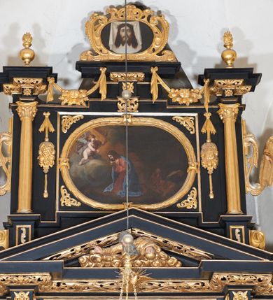 Zdjęcie nr 8: Ołtarz architektoniczny, jednoosiowy, dwukondygnacyjny, z bramkami, na cokole. Pierwsza kondygnacja ujęta parą pilastrów za dwiema parami gładkich kolumn o kapitelach kompozytowych, dźwigających imposty, z gzymsem wyłamanym w partii podpór. Środkowa para wysunięta przed lico ołtarza, zwieńczona trójkątnym przyczółkiem z rzeźbą przedstawiającą Boga Ojca w obłokach. Pole środkowe w formie arkady z obrazem Ukrzyżowania. Kondygnacja ujęta uszami utworzonymi z ornamentu małżowinowo-chrząstkowego. Na bramkach figury św. Piotra i św. Pawła. Druga kondygnacja w formie leżącego prostokąta, ujęta parą pilastrów i stojącą przed nimi parą gładkich kolumn o kapitelach kompozytowych, dźwigających imposty. Kondygnacja flankowana dwiema figurami aniołów stojących na postumentach. Pole obrazowe z przedstawieniem Chrystusa w Ogrójcu w formie leżącego owalu w prostokątnej płycinie. Zwieńczenie przyjmujące kształt impostu dźwigającego na szerokim gzymsie owalny kartusz ujęty ornamentem małżowinowo-chrząstkowym z przedstawieniem Veraicon. Nastawa pokryta bogatą dekoracją ornamentalną. W partii cokołów płyciny z ornamentem małżowinowo-chrząstkowym, w wewnętrznych dodatkowo główki anielskie oraz girlandy utworzone z tkaniny nad arkadami bramek. Czoło arkady pola środkowego dekorowane rozetami, w ościeżach bocznych małżowina, w podłuczu kasetony z rozetami. W przyłuczu arkady ornament roślinny. W impostach, w partii fryzu rozety, powyżej ażurowy ornament małżowinowo-chrząstkowy dekoruje podstawę gzymsu. Przyczółek ozdobiony małżowiną. W drugiej kondygnacji owalna rama obrazu przyjmuje postać wieńca laurowego dekorowanego kartuszami z kaboszonami. W narożach płyciny małżowina. Pole ujęte festonami utworzonymi z tkaniny, owoców i kwiatów. Fryz impostów dekorowany analogicznie jak w pierwszej kondygnacji. Na fragmentach belkowania wazony. Odcinki gzymsu połączone girlandą z tkaniny z pękiem owoców i kwiatów. Kondygnacja ujęta uszami z ornamentu małżowinowo-chrząstkowego. 
Ołtarz kamienny z drewnianą obudową i mensą z portatylem. Antepedium w formie leżącego prostokąta, ujęte ornamentalną ramą z motywem akantu. W polu purpurowa tkanina z haftowanym monogramem IHS. Nastawa polichromowana na kolor czarny ze złoconymi kolumnami, detalami architektonicznymi i ornamentyką.