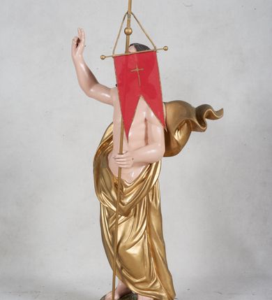 Zdjęcie nr 2: Rzeźba pełna przedstawiająca Chrystusa Zmartwychwstałego w całej postaci, w kontrapoście. Prawą rękę ma zgiętą w łokciu, uniesioną w geście błogosławieństwa, w lewej trzyma drzewiec zakończony krzyżem i proporcem. Głowa uniesiona, twarz okalają ciemne długie włosy i krótka broda. Płaszcz malowany na złoto, udrapowany wokół pasa odsłaniając nagi tors, za plecami rozwiana kaskada fałd. Podstawa rzeźby półkolista, polichromia w partiach ciała naturalistyczna. 