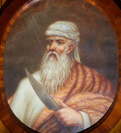 Zdjęcie nr 1: Obraz w kształcie owalu z przedstawieniem Abrahama ukazanego w popiersiu, zwróconego w prawą stronę z nożem w lewej dłoni. Twarz pociągła o rysach starca, okolona siwymi włosami i długą, siwą brodą. Abraham ubrany jest w białą suknię z długimi rękawami, jasnobrązowy płaszcz zdobiony w czerwone paski oraz biały turban na głowie. Tło jednolite brązowe, po lewej stronie niewielkie obłoki z promieniami. Rama drewniana, fornirowana, politurowana.